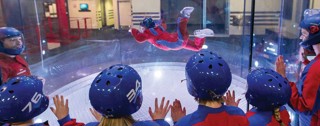 Person flying at iFLY while observed by a roup of people